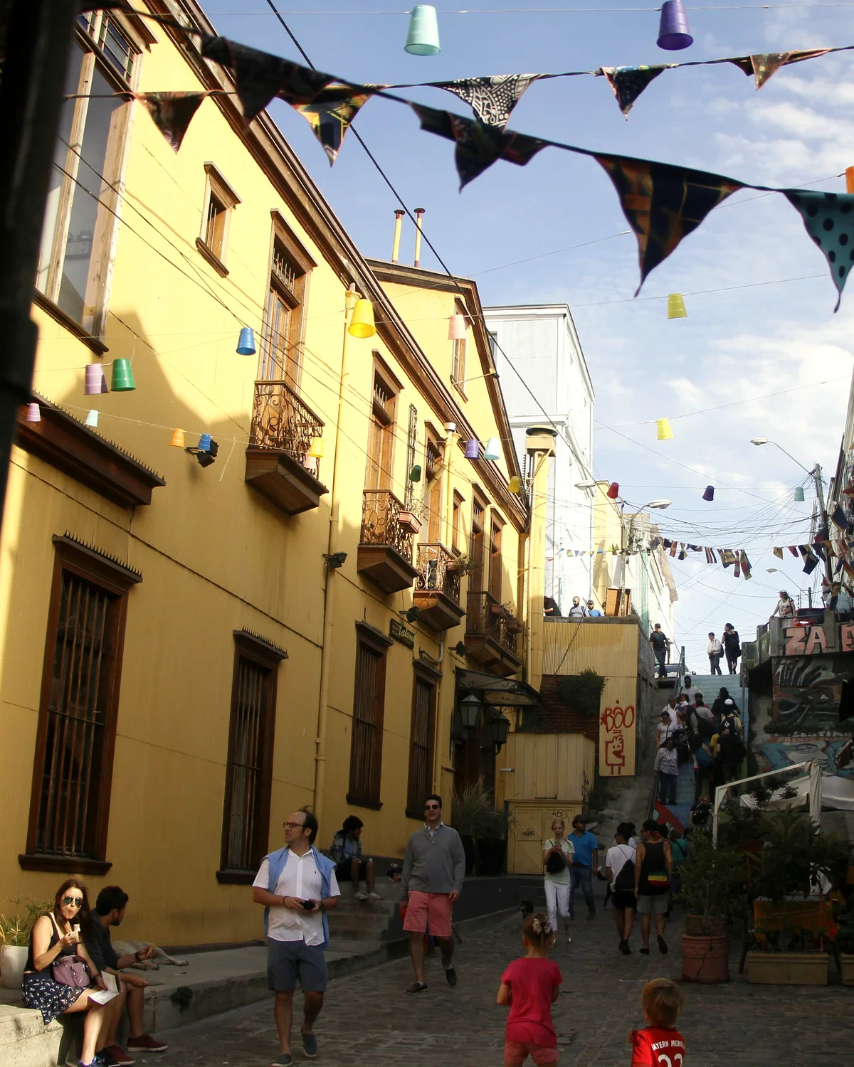Calle de cerro en Valparaíso con banderines de colores y personas caminando
